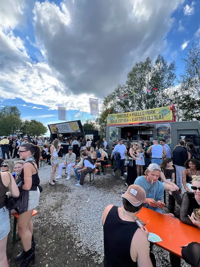 Gäste an Biertischen vor den Häge-Trucks Rita's Spätzle und Loaded Fries
