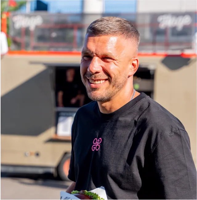 Lukas Podolski lacht vor dem Häge-Foodtruck auf dem Glücksgefühle Festival